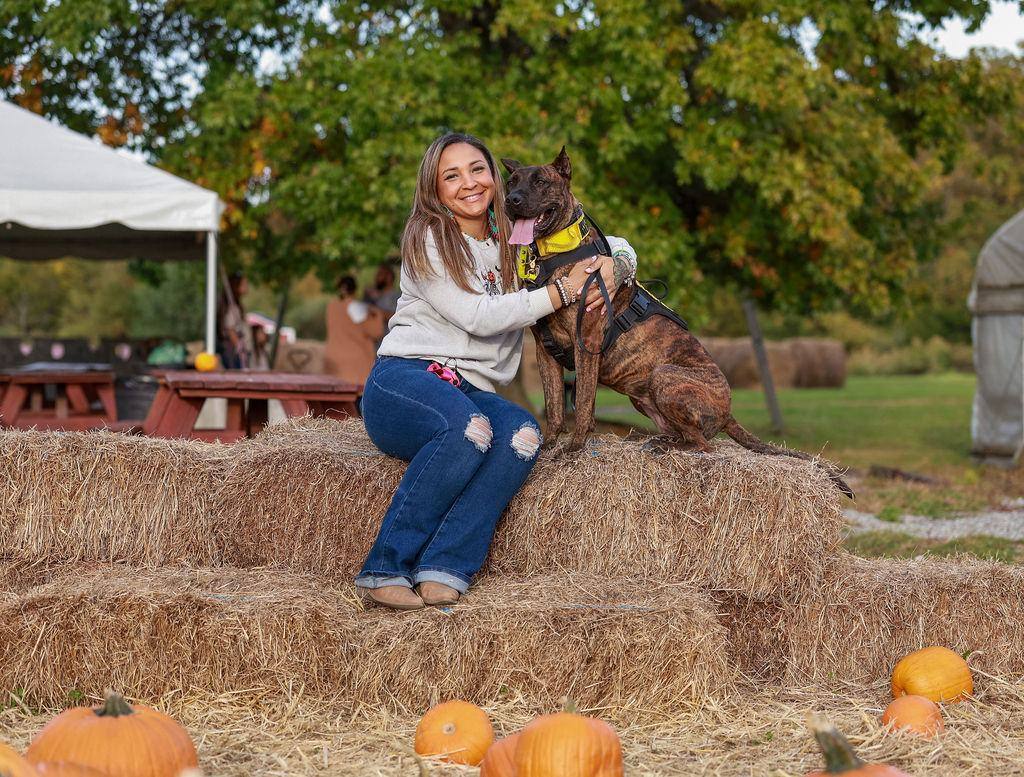 Woman and her dog on hay bales at a fall farm day